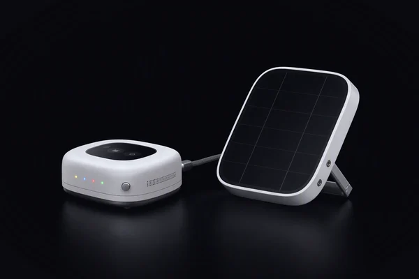 A small compute node with four coloured lights, cabled to a tilted solar panel tile